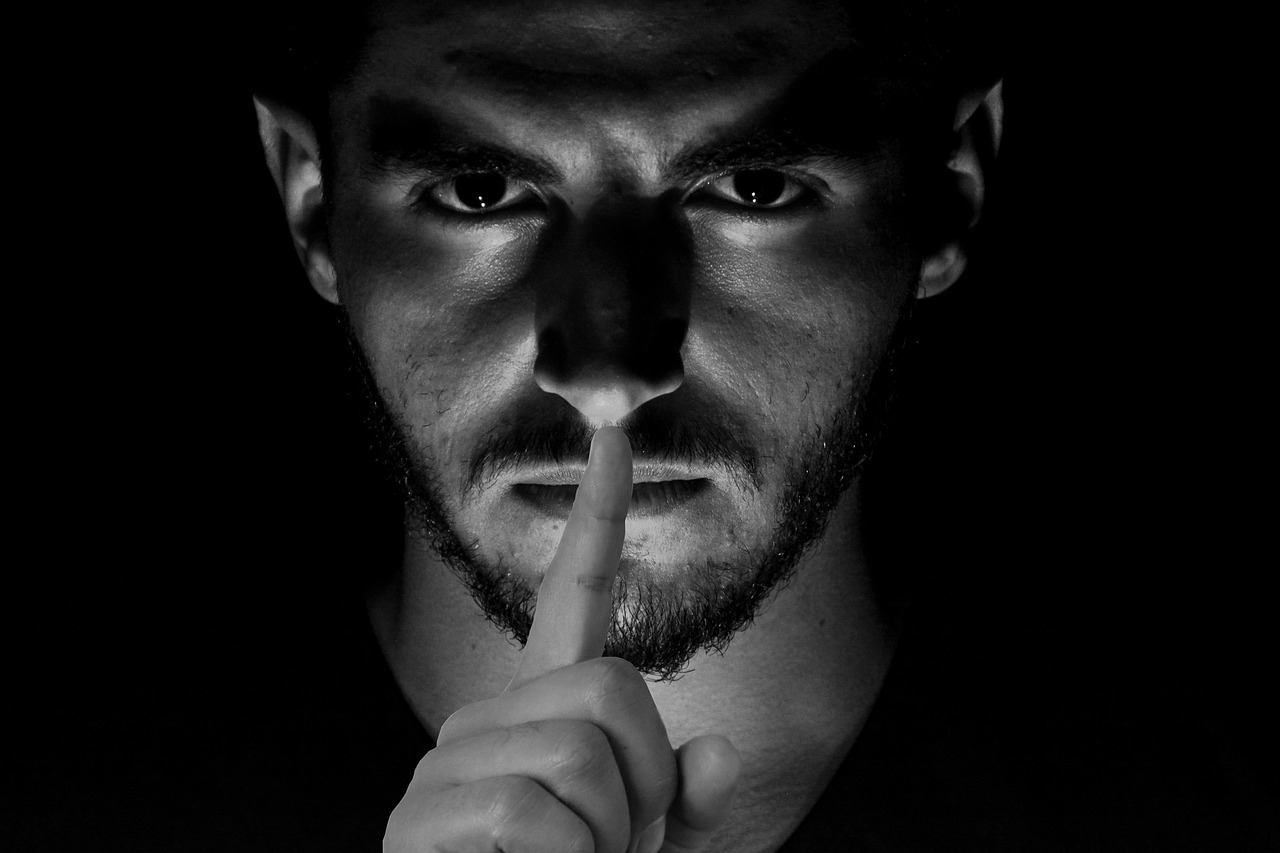 Photo of man's face with finger over mouth